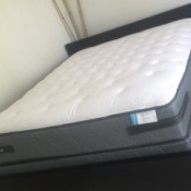 A brand new mattress on a bedframe.