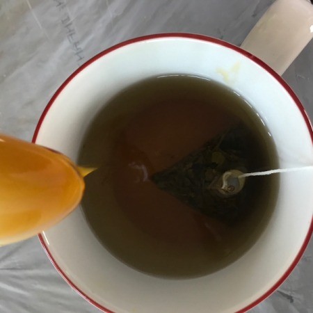 honey added to mug with tea bag