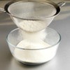 Sifting flour using a metal strainer.