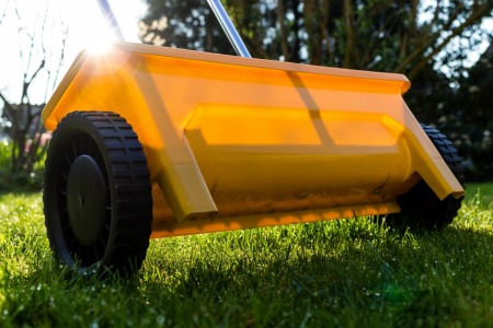 A yellow lawn fertilizer broadcast spreader.