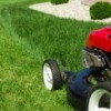 A red lawn mower being using to mow a lawn.