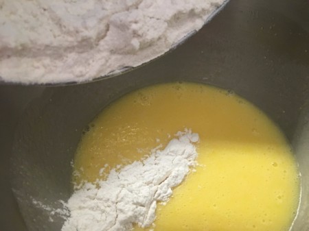 adding flour mixture to egg