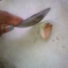 Using the back of a spoon to crush garlic.