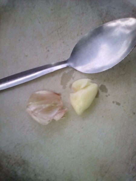 Using the back of a spoon to crush garlic.