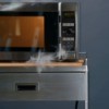 A microwave is smoking from a fire inside.