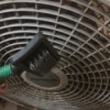 Cleaning a fan with a wire dog brush.