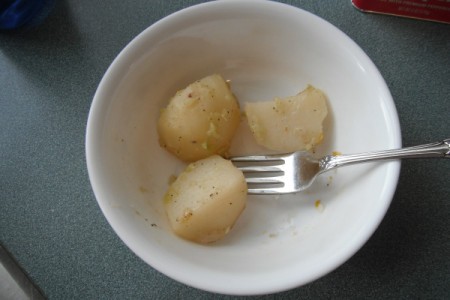 Chunks of potato in a white bowl with a fork.