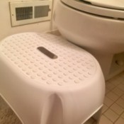 A white step stool next to a toilet.