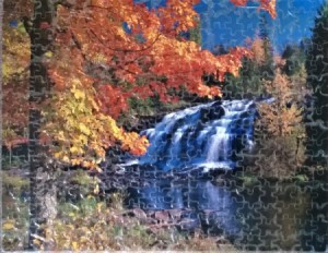 A finished puzzle of a waterfall in autumn.