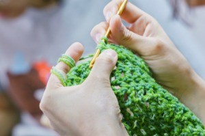 A crochet craft being made with green yarn.