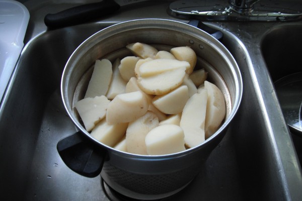 A pan full of cut and peeled red potatoes.