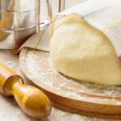 Photo of rising bread dough with a towel draped over it.