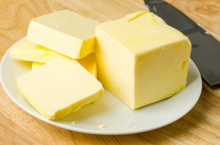 A stick of butter on a plate.