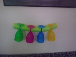 Four plastic wine glasses held by a pool noodle.