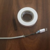 A frayed electronic charging cord, with a spring and a roll of electrical tape.