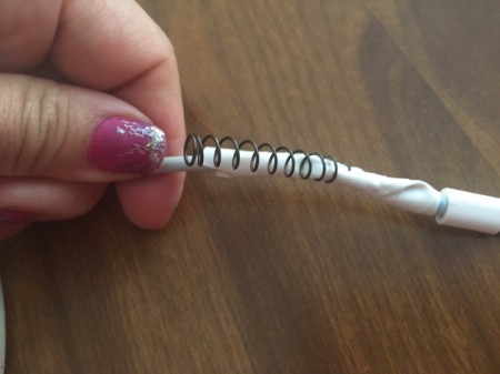 Placing the spring over the repaired portion of the electronic cord.