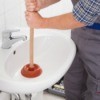 A plumber user a plunger in a bathroom sink.
