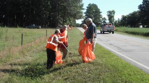 A group of people cleaning up litter on the side of a road.