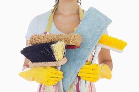 A professional cleaner holding cleaning supplies.