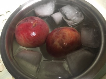 Placing a peach in ice water to remove the skin.