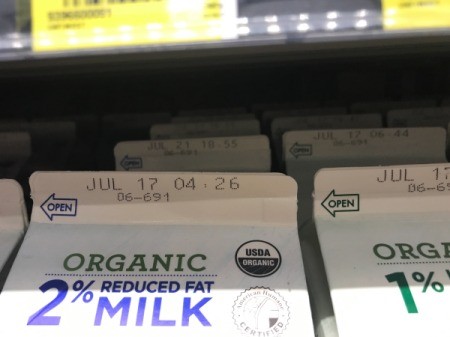 A row of milk cartons with different expiration dates.