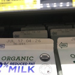 A row of milk cartons with different expiration dates.