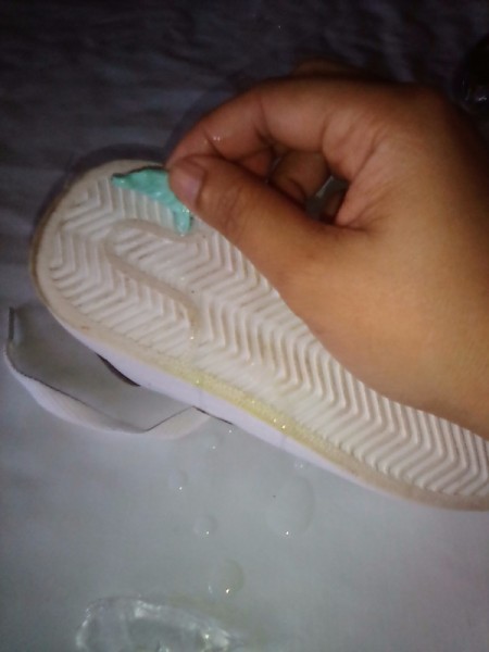 Removing the gum from the sole of a shoe.
