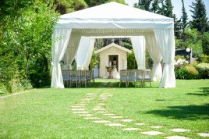 An outdoor wedding with seating a large white canopy.