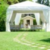 An outdoor wedding with seating a large white canopy.