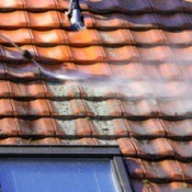 Cleaning a red tile roof.