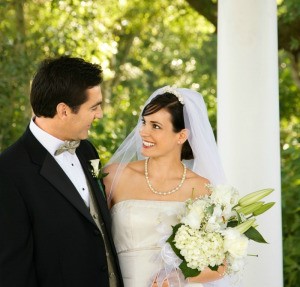 A bride and groom standing next to a white column.