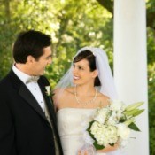 A bride and groom standing next to a white column.