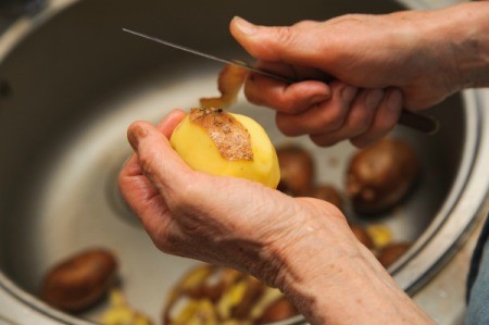 Peeling potatoes into a sink with a garbage disposal.