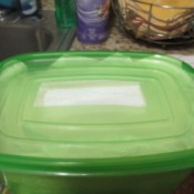A plasticware container filled with paper towels, with a hole in the lid.