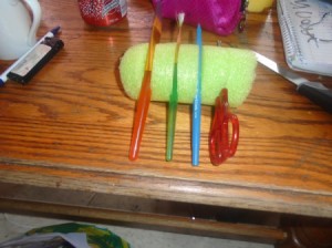 A pool noodle with slits to hold brushes.