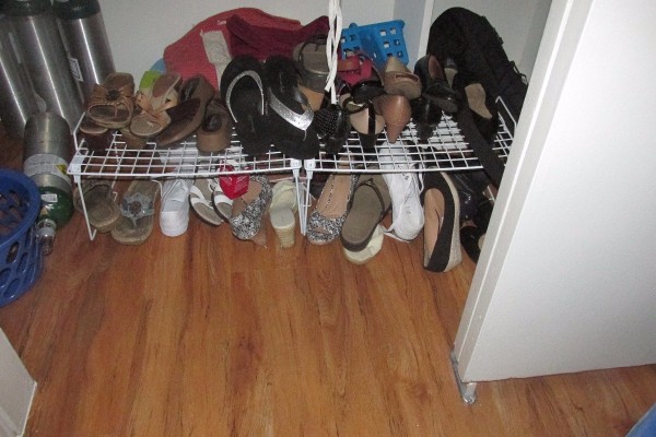 Shoes organized on a rack on the floor of a closet.