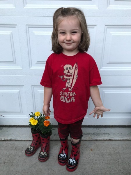Rubber Boot Planter - child wearing new boots and standing next to planted boots