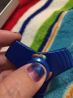 A blue fidget spinner being held between fingers.