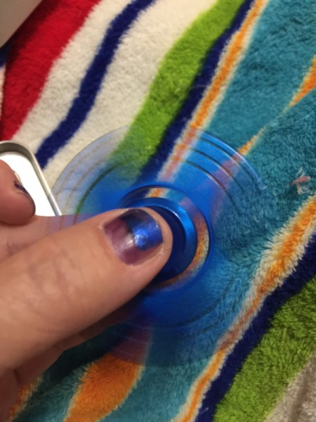 A blue fidget spinner being spun between fingers.