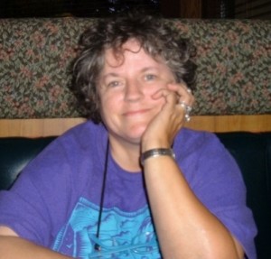 A smiling woman sitting in a restaurant booth.