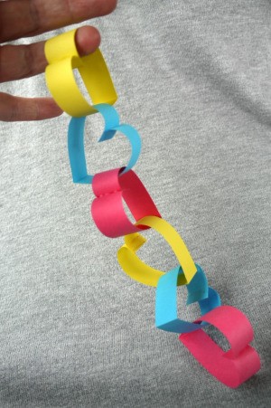 Heart Shaped Paper Chain - hand holding a short length of heart shaped paper chain links, connected