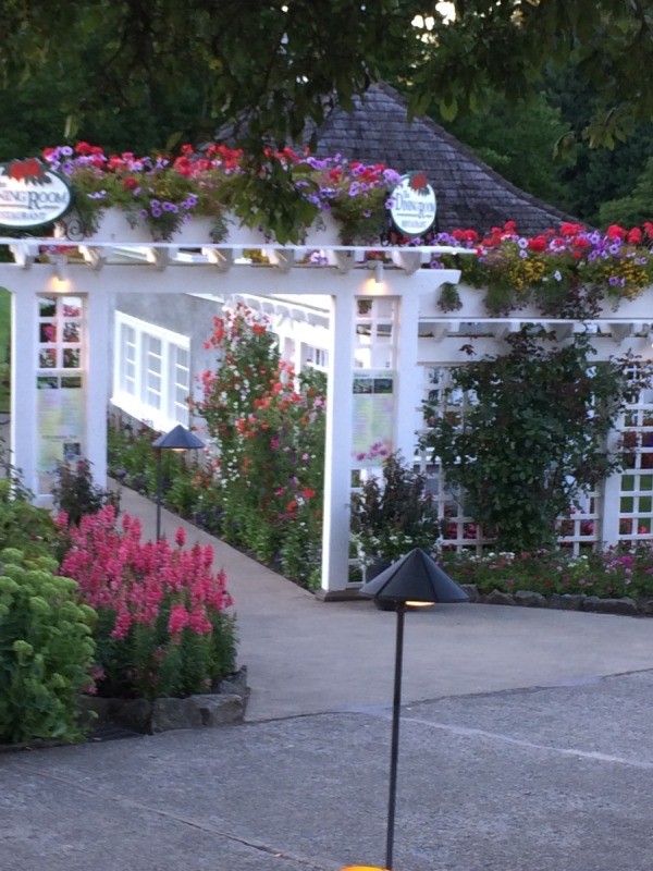 A white structure with blooming plants all around, at Butchart Gardens.