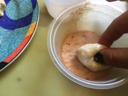 rolling dough piece in cinnamon sugar mixture