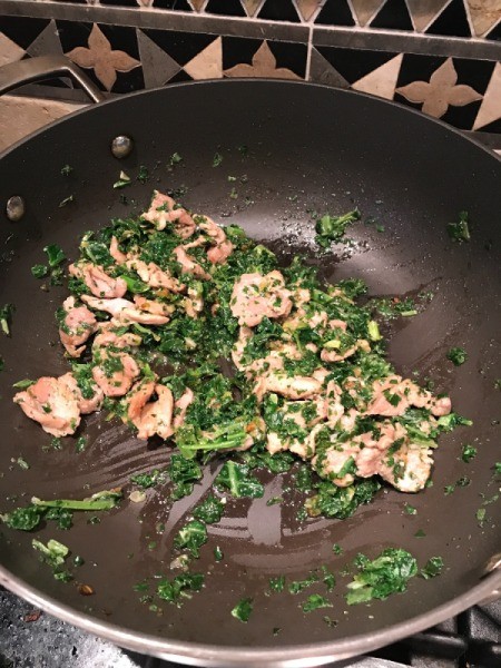 kale/spinach added to pork and onions in wok