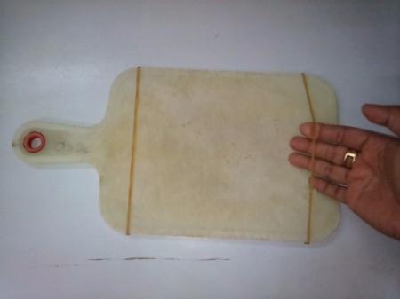 Placing rubber bands on the sides of a cutting board.