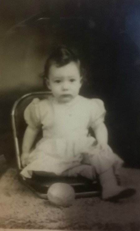 A vintage photograph of a young girl with a pretty dress.