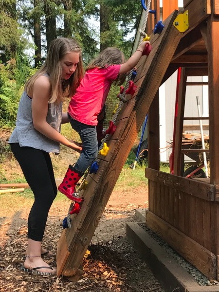 Refinishing a Wooden Playground - young boy climbing with the aid of his older sister