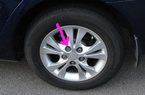 A car tire with a wheel lock on one of the five lug nuts.