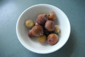 A white bowl containing several figs.