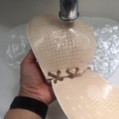 Washing an adhesive bra under a faucet.